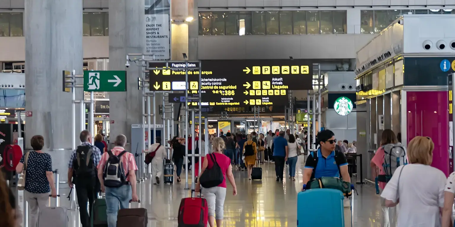 Reisende med kofferter i en flyplassterminal i Spania