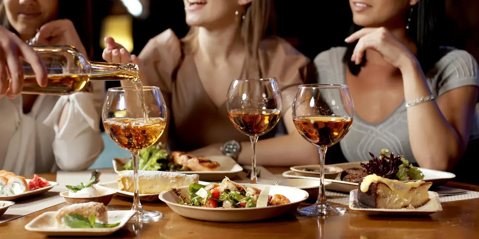 Väninnor delar mat och vin på restaurang